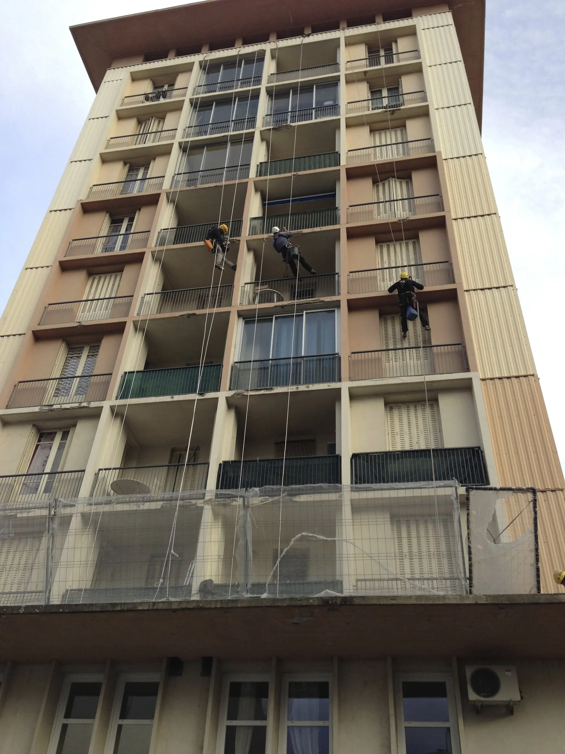 Plusieurs cordistes en intervention sur la façade d’une tour d’habitation