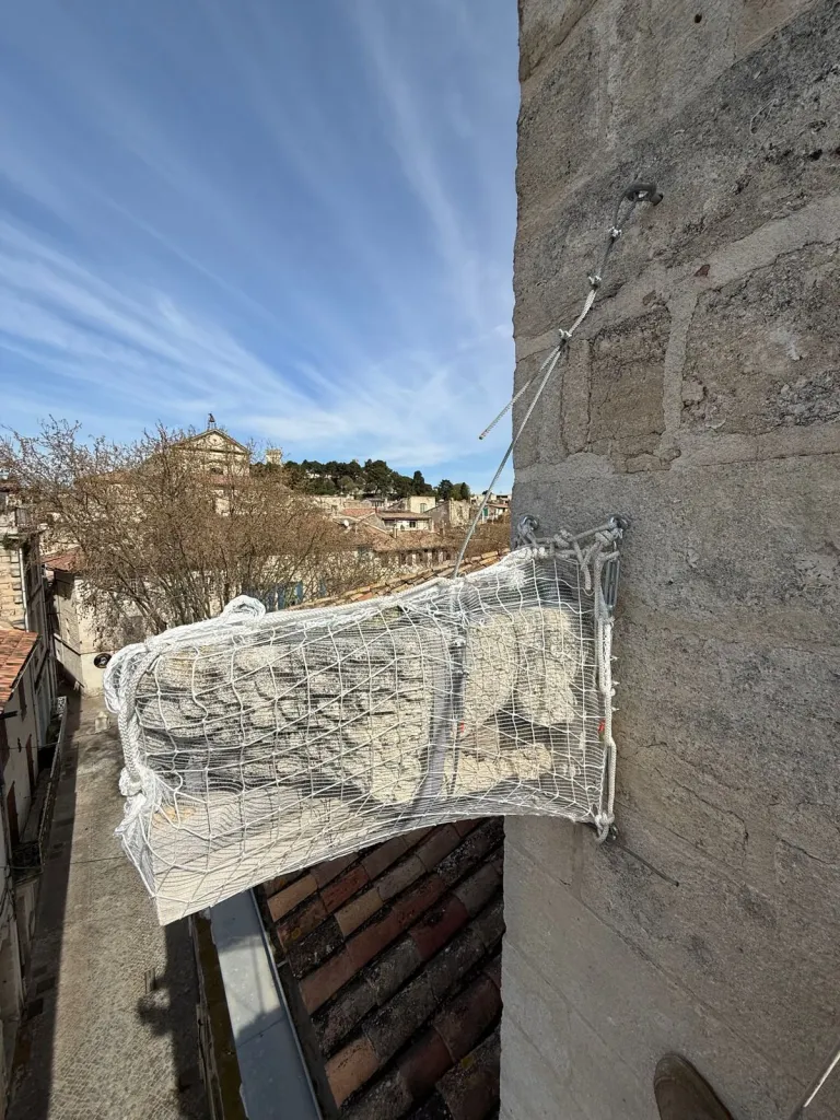Filet de protection installé sous une gargouille en pierre