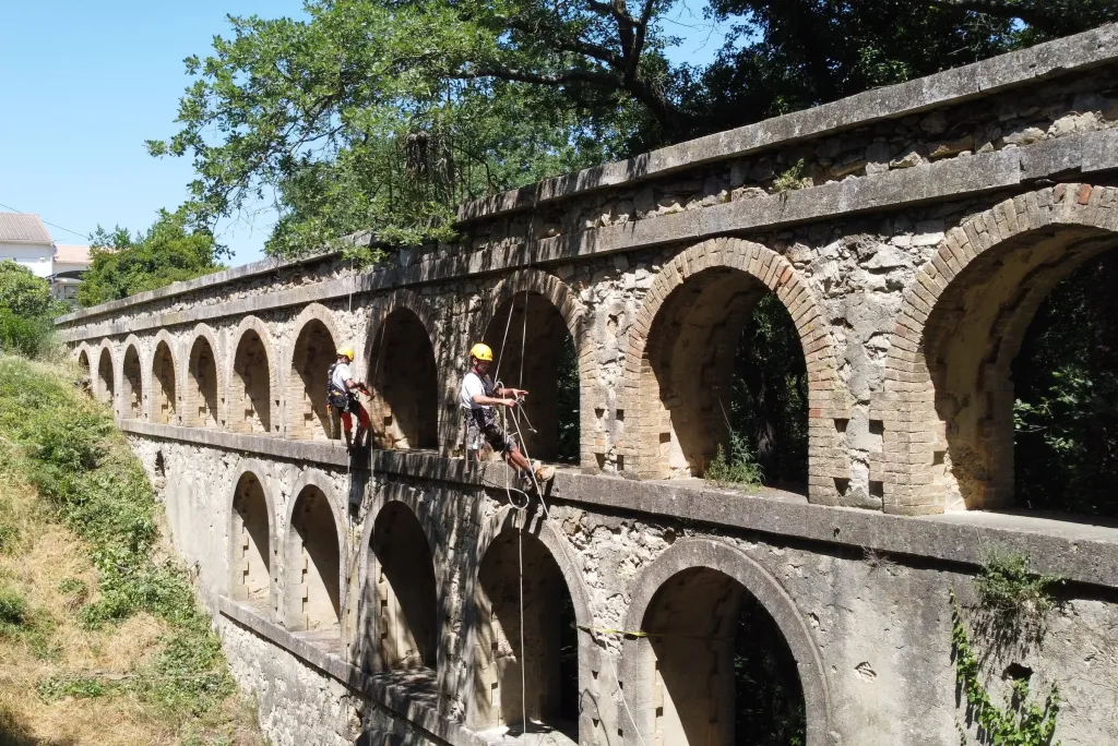 Deux cordistes d’Alpibat-Services en intervention sur un aqueduc en pierre à arches, vue de drone