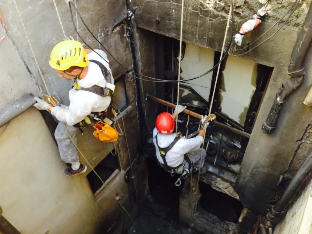 Deux cordistes en combinaison dans un espace confiné industriel