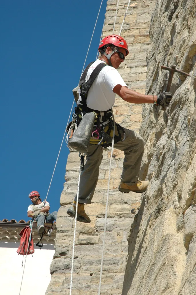 Cordiste travaillant sur le mur en pierre d’une église