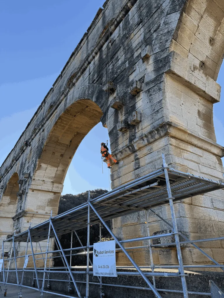 Cordiste en descente le long d’une pile du pont du Gard, au-dessus du platelage Alpibat-Services