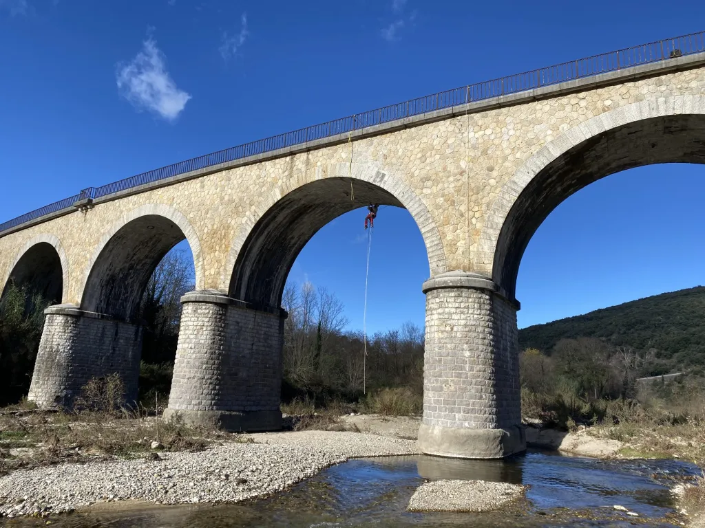 Le viaduc de Thoiras-Lasalle en pierre, avec un cordiste sur une arche