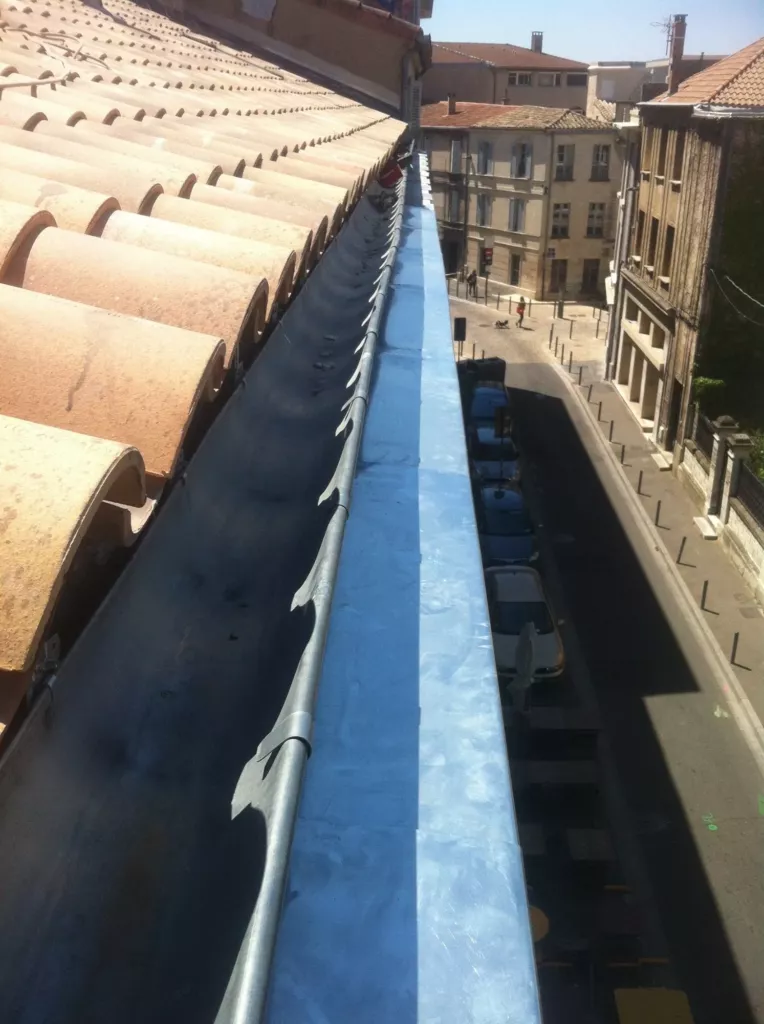 Chéneau en zinc neuf le long d’une corniche, au-dessus d’une rue