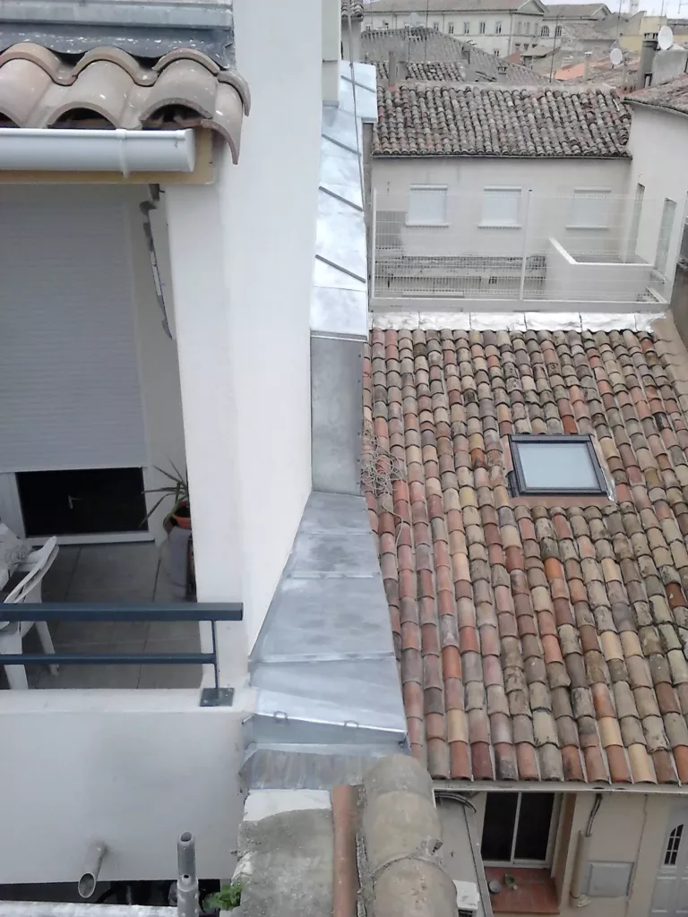 Couvertine en zinc posée sur un pignon, entre deux toitures en tuiles