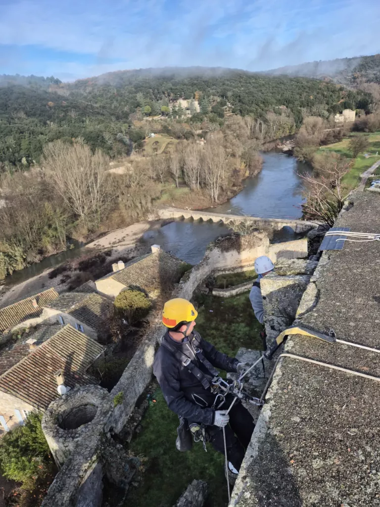 Cordiste vérifiant son descendeur au sommet du donjon de Montclus