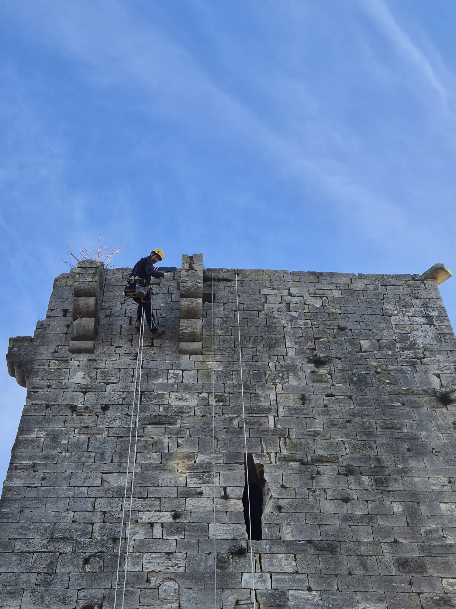 Le donjon de Montclus vu du sol, un cordiste au niveau des créneaux