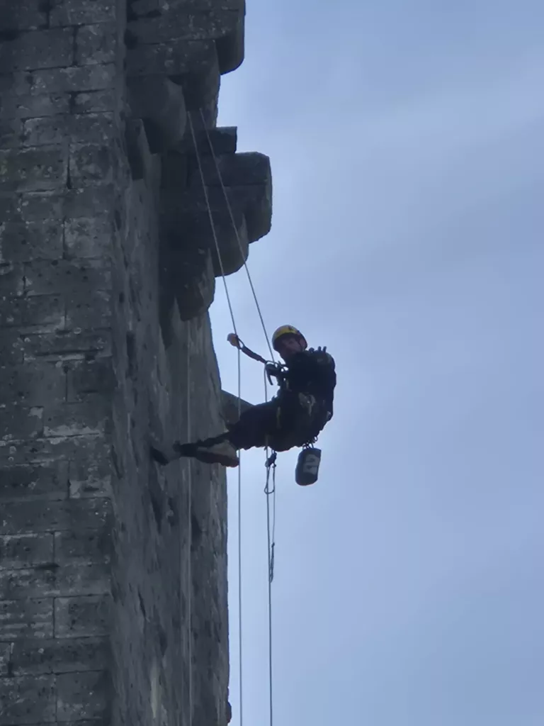 Cordiste en descente le long de la paroi du donjon de Montclus